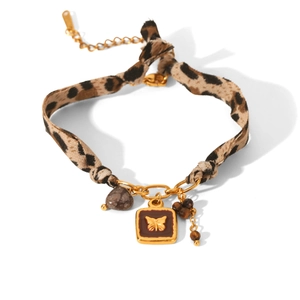 Detail of leopard print fabric bracelet with butterfly enamel charm and golden hardware