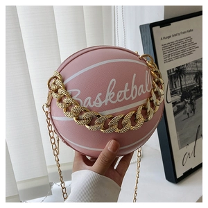 Detail of pink basketball shaped crossbody bag with gold chain strap and textured finish