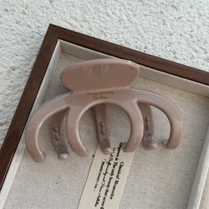 Macro detail of beige glossy hair claw clip with gold engraving in a wooden box