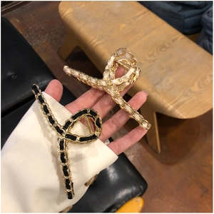 Detail of elegant gold metal hair claws woven with black and white silk ribbons