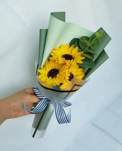 Close-up of three artificial sunflowers with eucalyptus tied with a striped ribbon
