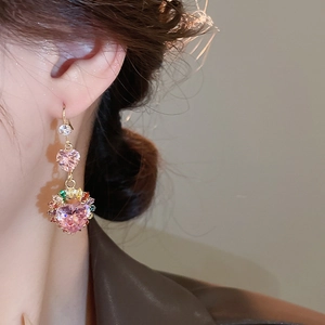 Close-up of model wearing pink heart-shaped zircon earrings with gold finish and colorful stones