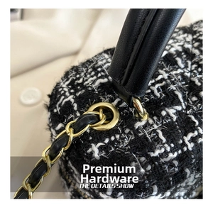 Macrodetail van hoogwaardige goudkleurige kettinghardware op een klassieke zwart-witte tweed tas