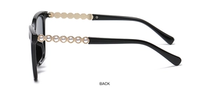 Detail of square black sunglasses with golden metal temples and white pearl accents