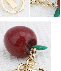 Detail of red glitter apple keychain with green leaf and golden metal link chain
