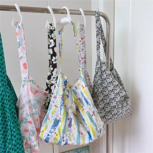 Detailed close-up of colorful floral print cotton tote bags hanging on a rack