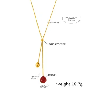 Detail of 18K gold plated snake chain with red resin and golden teardrop charms