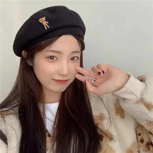 Close-up of black wool beret side featuring a 3D teddy bear decorative element