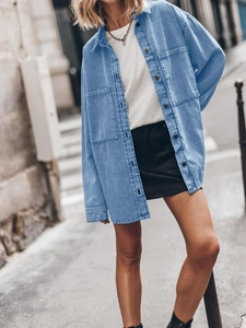 Close-up of women's retro light blue denim shirt with large pockets and button details