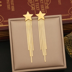 Golden long fringe star earrings hanging from a brown jewelry box with vintage book