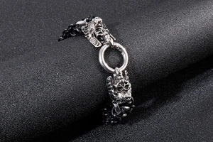 Detailed close-up of punk style stainless steel skull and wolf head on braided leather bracelet