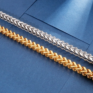 Macro detail of gold and silver stainless steel keel chain necklaces on a blue surface