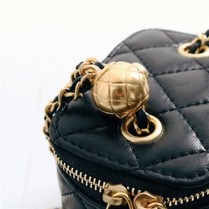 Detail of black quilted lambskin leather bag with signature golden ball chain adjuster