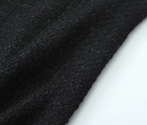 Macro detail showing the rich texture of black tweed fabric with woven fibers