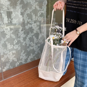 Detail of white mesh tote bag with canvas base held by a model in a natural setting