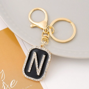 Macro view of golden letter N pendant with rhinestones and black enamel on keychain