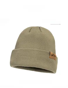 Detail of light green knit beanie featuring a brown leather patch with mountain logo