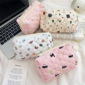 Detailed view of quilted makeup bags with cute prints and zipper closure in soft tones