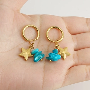 Detail of 18k gold plated star earrings with blue natural stone accents in hand
