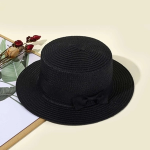 Detail view of the fine woven texture and black ribbon bow on a summer boater hat