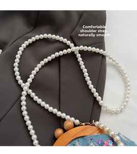 Detail of pearl bead strap and blue denim fabric with sequins on a small crossbody bag