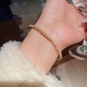 Detail of 18K gold plated bangle with sparkling cubic zirconia on female wrist