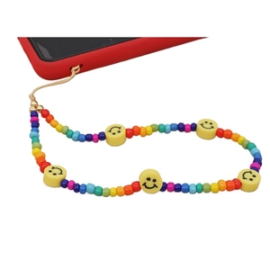 Colorful beaded phone strap with yellow smiley faces on a red mobile case accessory