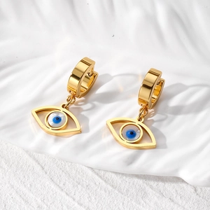 Detailed macro view of gold-plated evil eye hoop earrings on textured white background