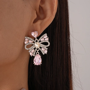 Gros plan détaillé d'une boucle d'oreille nœud en pierres roses portée par un mannequin