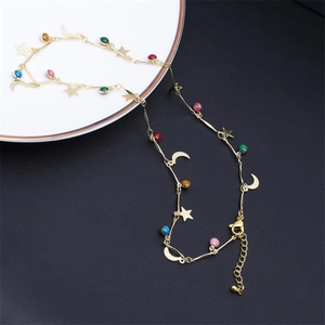 Detail of gold star and moon necklace featuring multi-colored gemstones and lobster clasp