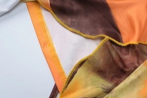 Macro detail of tie-dye print dress showing yellow overlock stitching and knit fabric