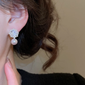 Close-up of elegant flower pearl earring with cubic zirconia studs on a female model
