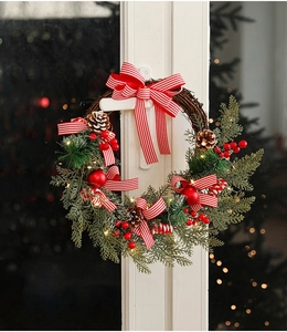 Close-up of Christmas wreath with pine cones, red berries, and warm LED lights on a door