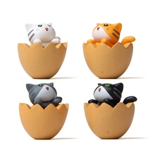 Detail of four miniature cats emerging from brown eggshells for micro landscape decor