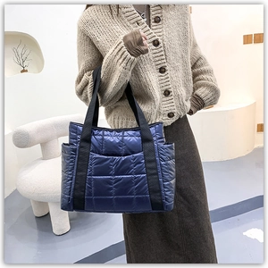 Macro detail of navy blue quilted tote bag fabric with glossy texture and side pockets