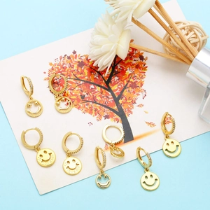 Detailed close-up of gold smiley face earrings with LOVE Me and BE HAPPY engravings