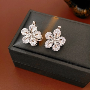 Vue macro de boucles d'oreilles fleurs argentées avec pétales en zircon et détails fins