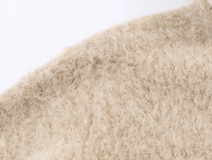 Gros plan détaillé sur la texture du tricot en peluche beige doux aux fibres bouclées