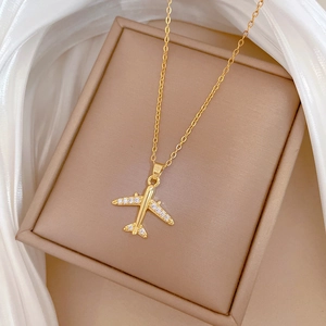 Luxurious gold airplane pendant necklace with sparkling crystals on a white silk display