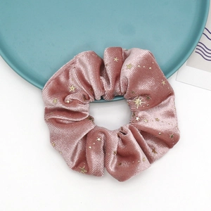 Detail of pink velvet scrunchie featuring gold foil stars and sequins on soft fabric