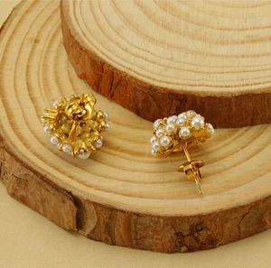 Detailed close-up of 18k gold pearl cluster earrings on a rustic wooden base background