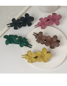 Flat lay of floral hair clips in black, green, and brown matte finish on a white surface