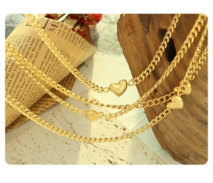 Detailed close-up of 18K gold heart pendant necklaces hanging on creative props