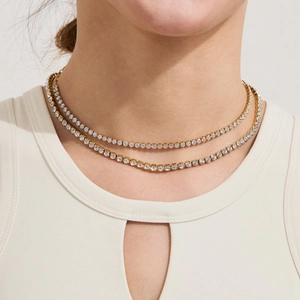 Close-up of double-layered gold tennis necklaces with zircon stones on female model