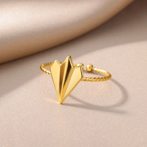 Detail of 18k gold plated paper plane ring with twisted band on silk background