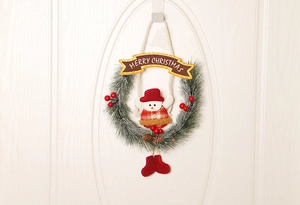 Detail von Weihnachtskranz mit Schneemann, Tannennadeln und Merry Christmas Schild an weißer Tür