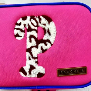 Close-up of pink shoulder bag featuring chenille P patch and gold logo brand plate