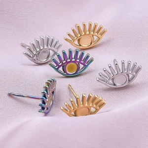 Close-up of 304 stainless steel eye earrings in gold, silver and rainbow on pink silk