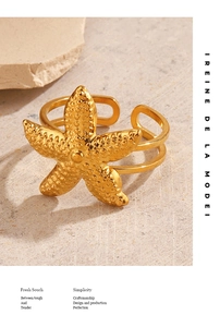 Detailed view of a gold starfish wrap ring on a textured stone, ocean style jewelry