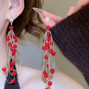 Detailed shot of long red beaded tassel earrings with gold woven strings and clear zircon
